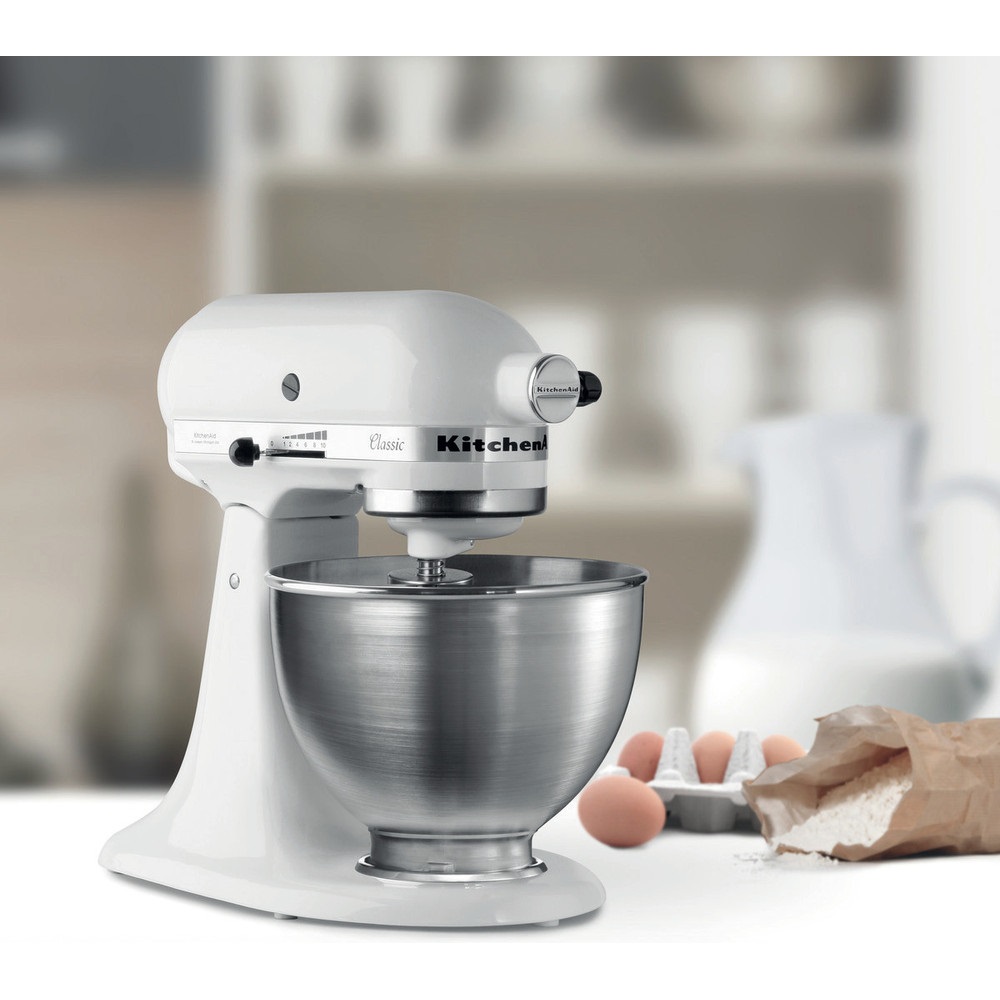 Lifestyle image of the KitchenAid 5K45SSSEWH stand mixer on a kitchen counter with ingredients.