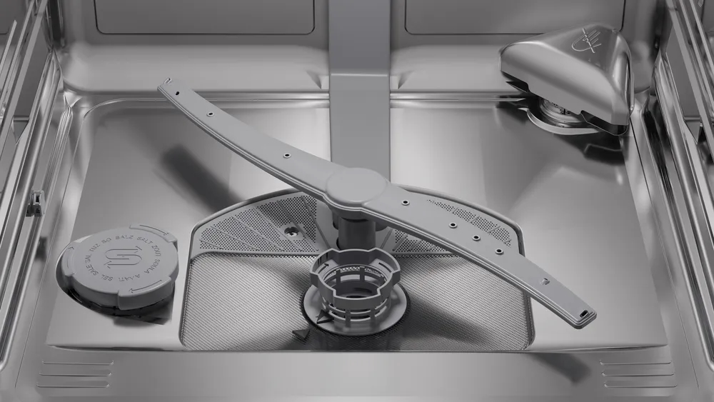 Detailed view of the stainless steel bottom featuring the spray arm, filter system, and salt reservoir cap.