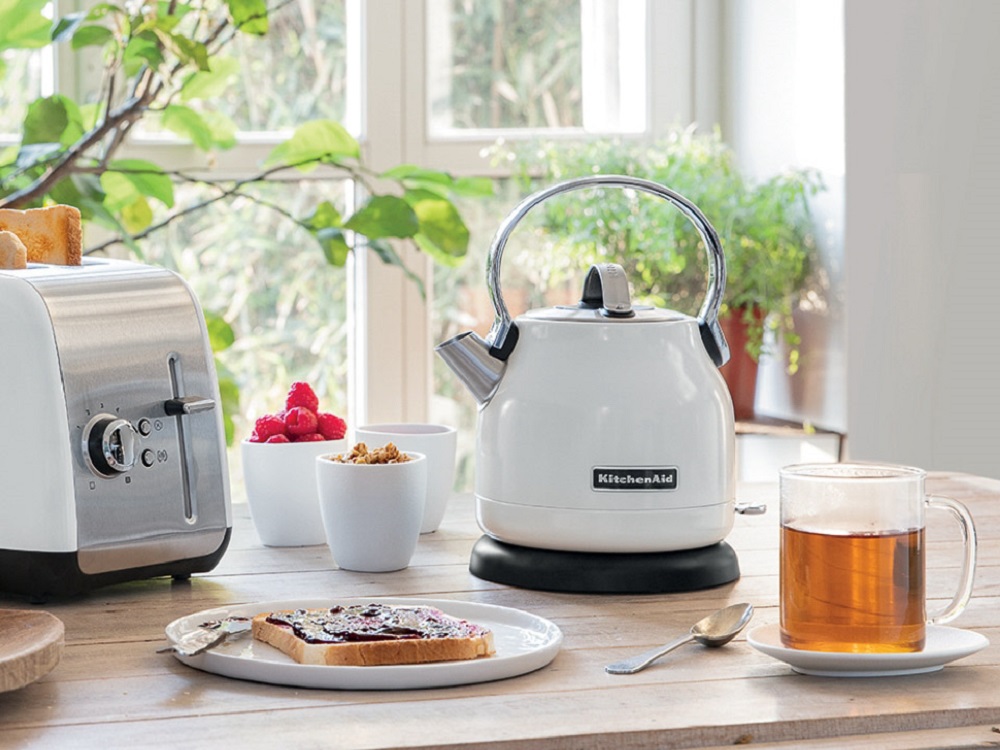 KitchenAid 5KEK1222EWH kettle in White alongside a matching toaster on a kitchen table.