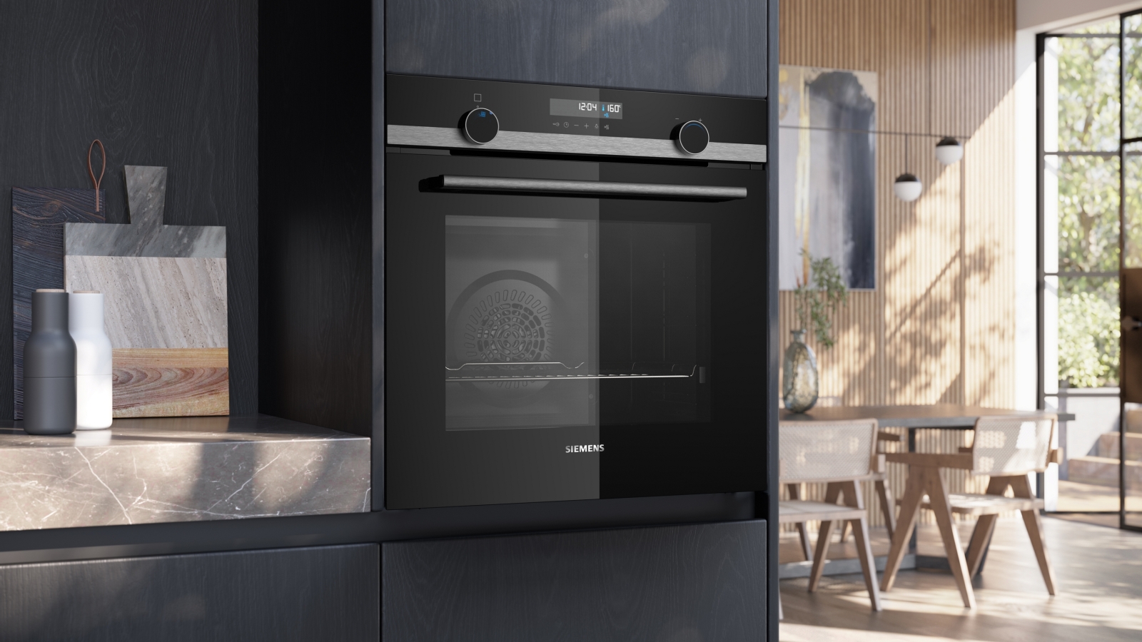 The Siemens HB578GES3 oven is closed and integrated into dark kitchen cabinetry, with a view into the dining area.