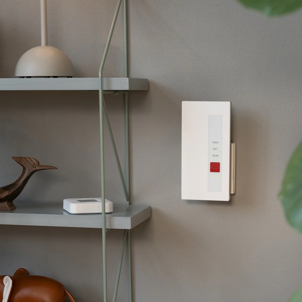 The AVM FRITZ! Zigbee Gateway mounted on a light grey wall, illustrating its integration into a modern Smart Home environment.