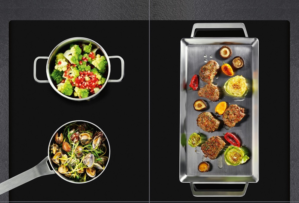 AEG IKE64441XB induction hob in action, showing various pots and a griddle on the flexible cooking zones.
