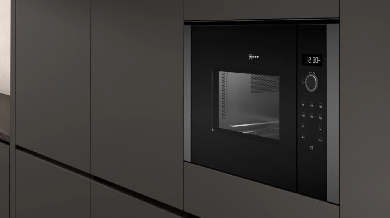 The NEFF microwave installed into a kitchen wall cabinet, complementing the modern, dark kitchen design.