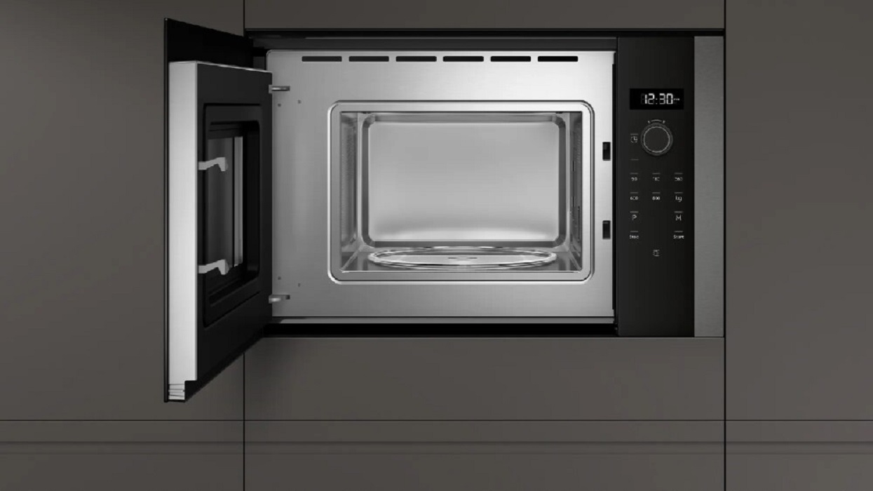The door of the NEFF microwave is open, showing the turntable and the illuminated stainless steel cooking cavity.